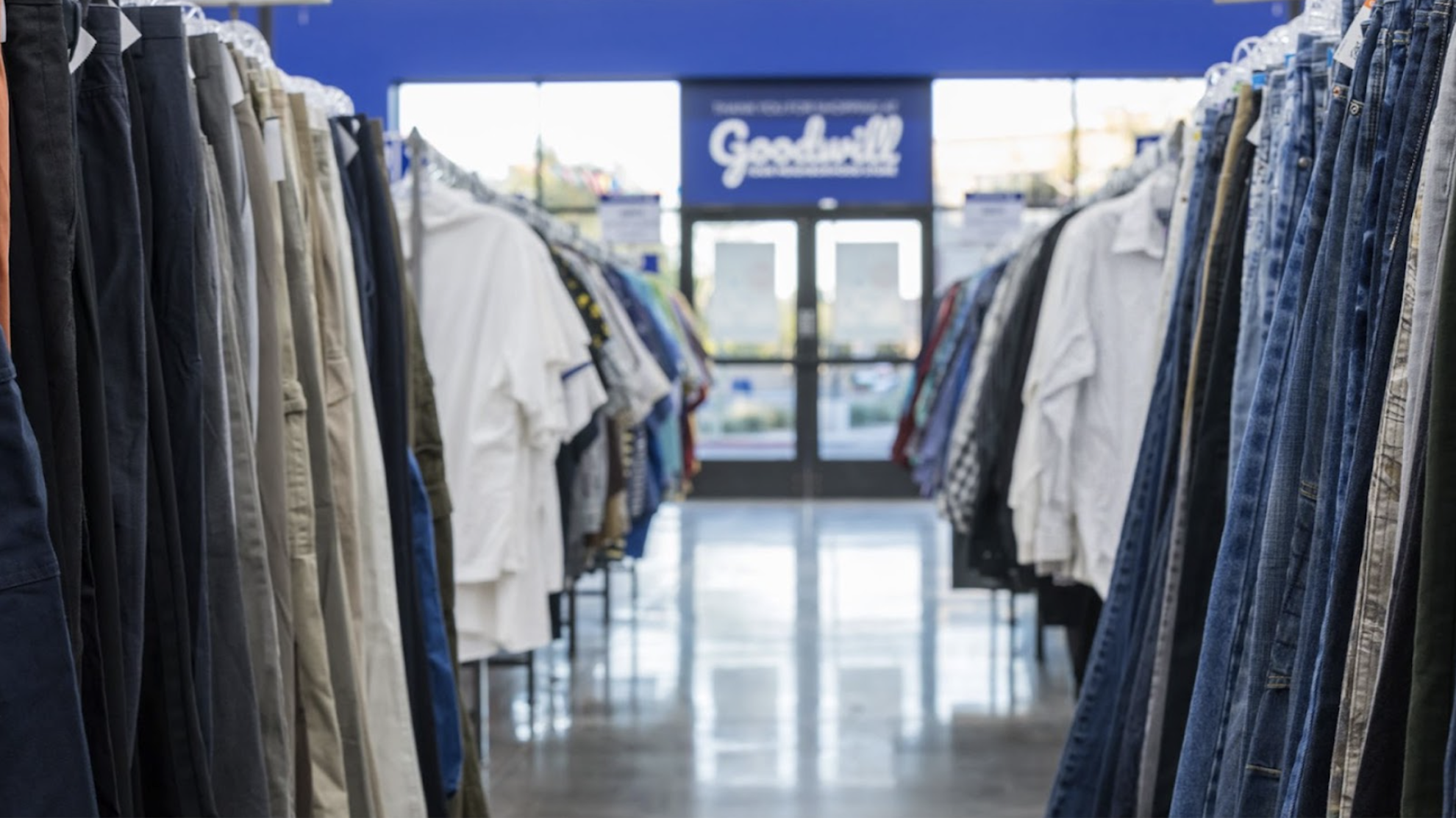 Goodwill AZ | Someone looking through racks of white shirts on hangers